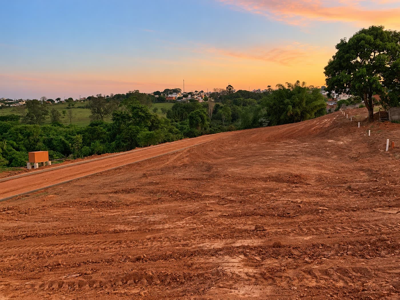 Vista do Loteamento Passos ao pôr do sol, com vias e o vale ao fundo